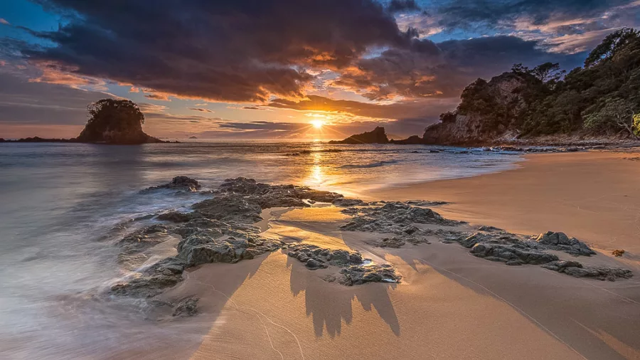 Sunset over Cathedral Cove rock formation on Coromandel Peninsula