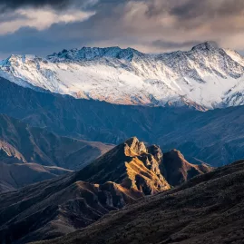 Dramatic mountain landscape from Skippers Saddle in Otago with snow-capped peaks and golden ridges