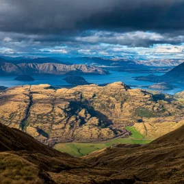 View of Lake Wanaka and Mou Waho Island from Treble Cone with rugged mountains and golden tussock