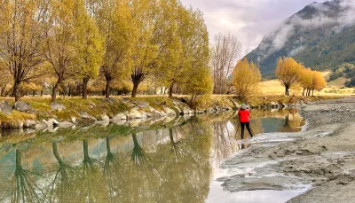 Photographer captures autumn trees reflecting in the still waters of the Shotover River, Central Otago, New Zealand.