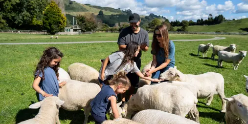 Family hand-feeding sheep during Agrodome Farm Tour in Rotorua