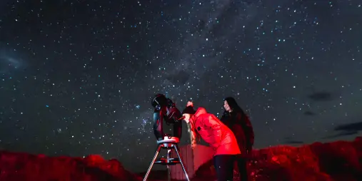 Two guests using telescope under starry sky during Crater Experience in Tekapo