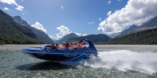 Side view of jet boat speeding across Dart River with spray