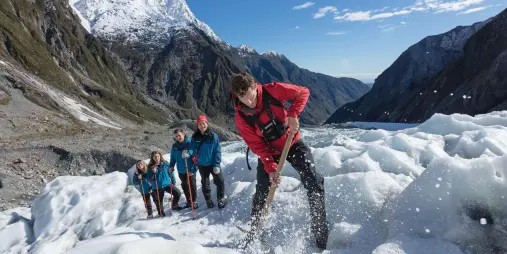 Glacier guide using ice axe to clear steps on Franz Josef