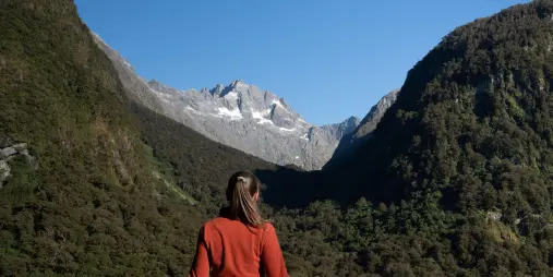 Visitor admiring the view from Hollyford Valley Lookout towards Fiordland’s alpine peaks