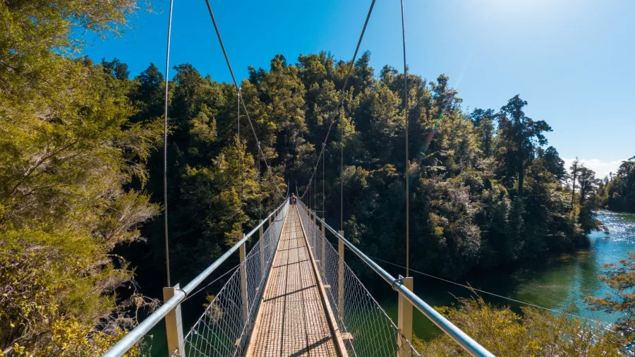 Walking across the Falls River suspension bridge in Abel Tasman on a sunny day