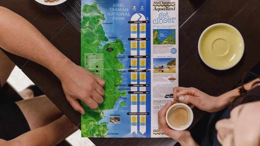 Couple planning their Abel Tasman trip with a map and coffee at Abel Tasman Lodge in Marahau