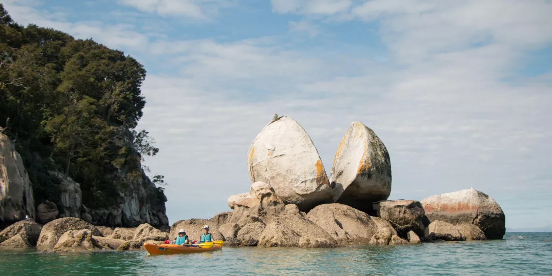 Kayakers near the iconic Split Apple Rock formation in Abel Tasman