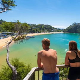 Two people enjoying the view from a lookout over Kaiteriteri Beach