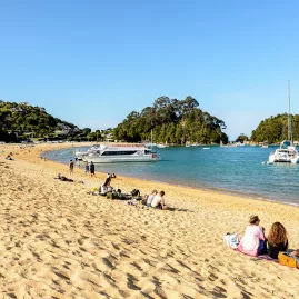 Kaiteriteri Beach with people relaxing and boats anchored near the shoreline