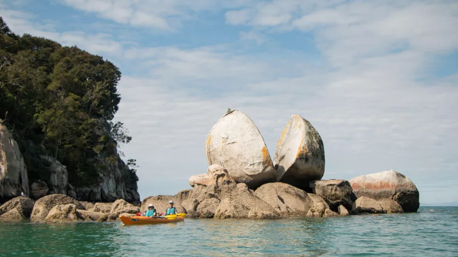Kayakers near the iconic Split Apple Rock formation in Abel Tasman