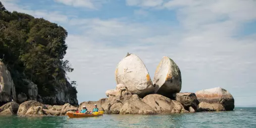 Kayakers near the iconic Split Apple Rock formation in Abel Tasman