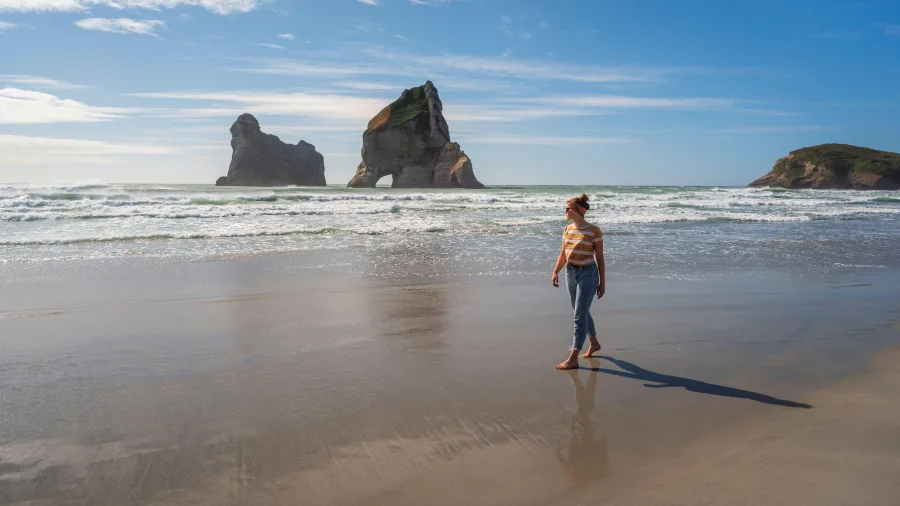 Person walking along Wharariki Beach in Golden Bay