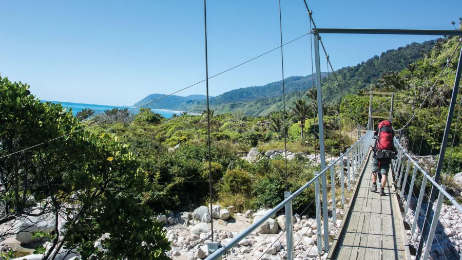 Walking across a suspension bridge on the Heaphy Track, Kahurangi National Park