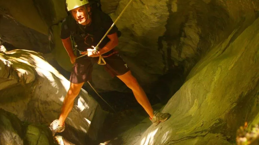 Canyoning guide standing at the bottom of Blue Creek canyon looking up during descent