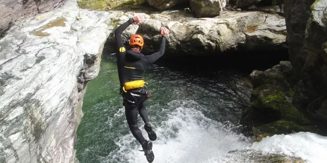 Canyoner mid-air jumping into a pool during the Doom Creek adventure