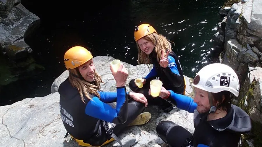 Canyoning group including a teenager taking a snack break by the water at Doom Creek canyon
