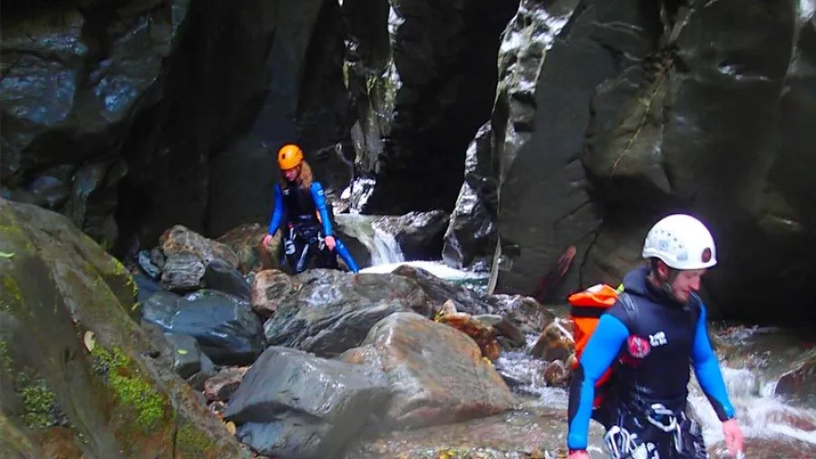 Canyoners hiking through narrow rocky terrain at Doom Creek, South Island