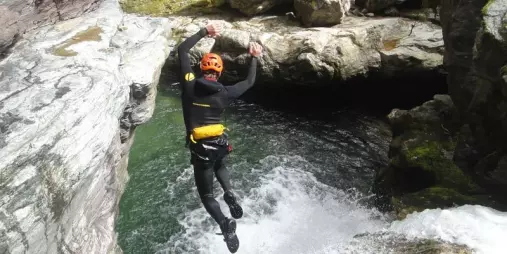 Canyoner mid-air jumping into a pool during the Doom Creek adventure