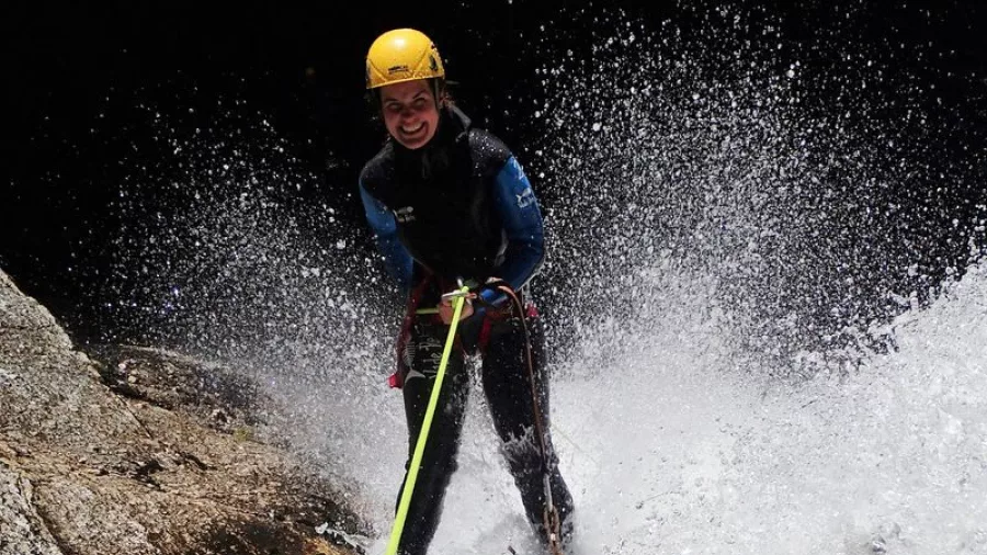 Canyoner mid-abseil with water splashing high around them in Falls River canyon