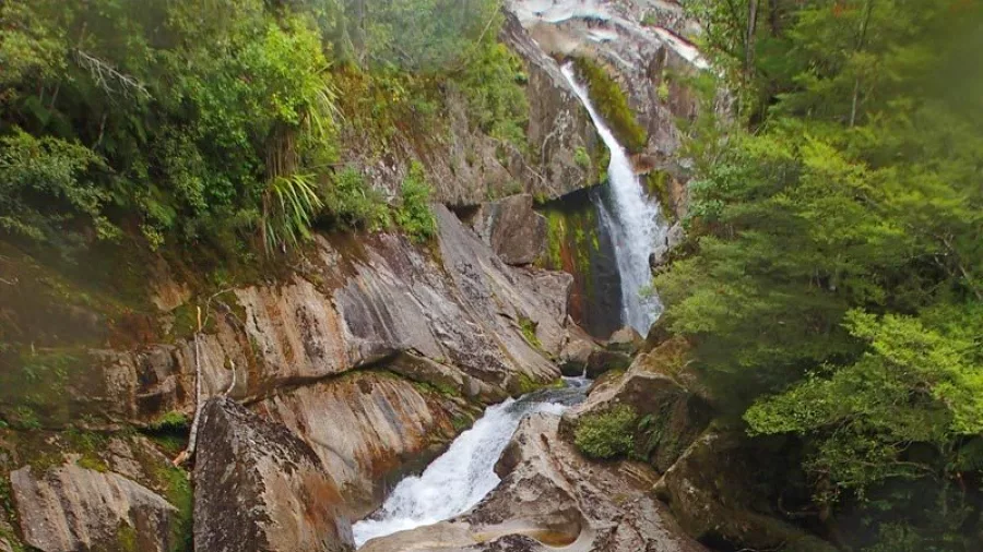 Scenic view of tiered waterfalls and rock formations in Falls River canyon, Abel Tasman