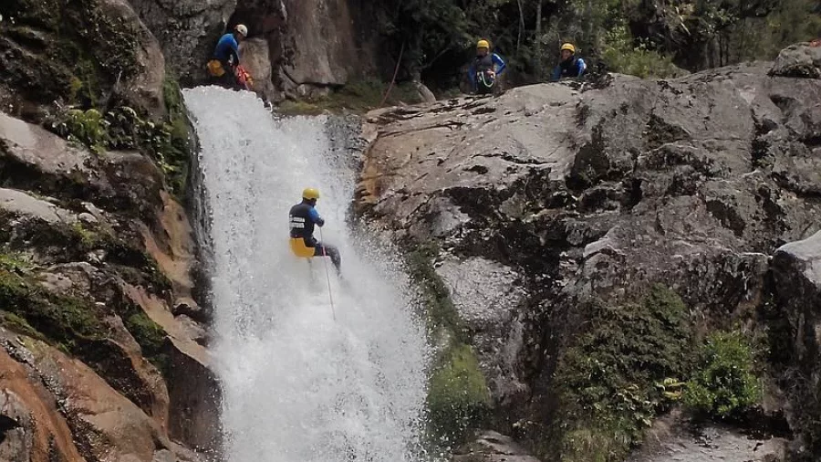 Canyoner descending a tall waterfall in Falls River canyon, Abel Tasman National Park