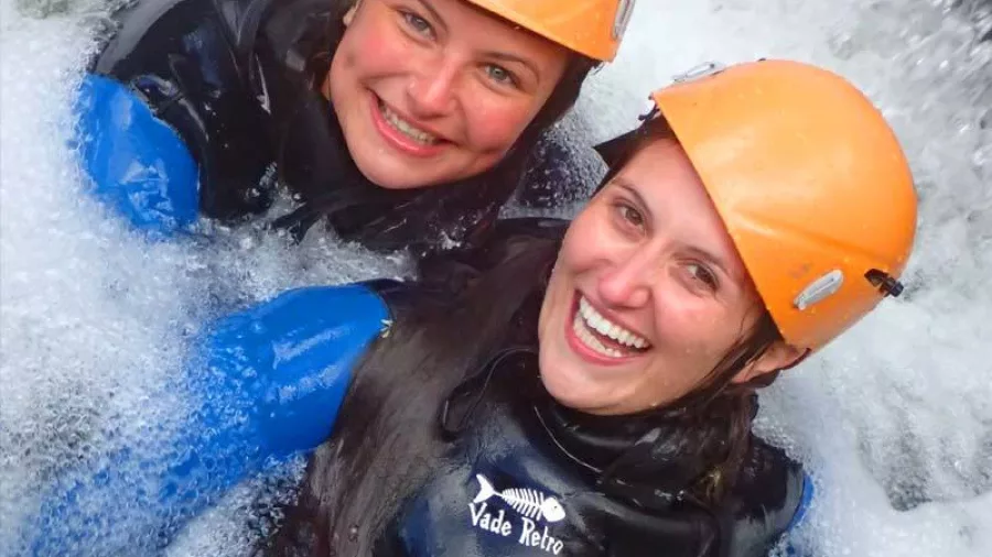Two canyoners smiling together in a foamy pool below waterfall in Torrent River canyon