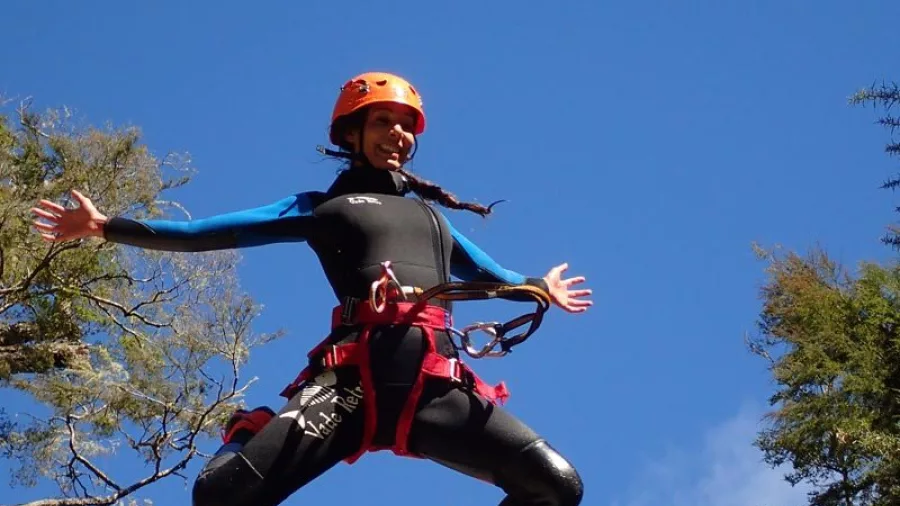 Canyoner mid-air during high jump with blue sky background at Torrent River