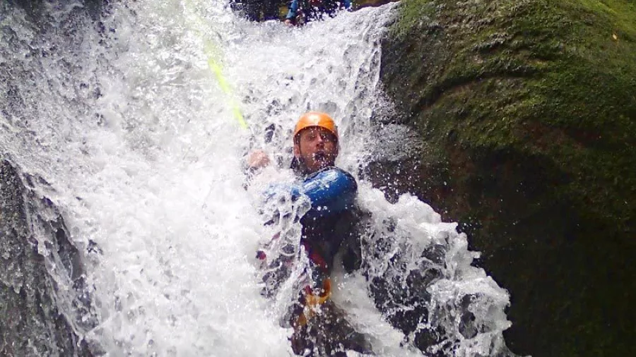 Canyoner on rope descending through a narrow torrent of water in Torrent River canyon
