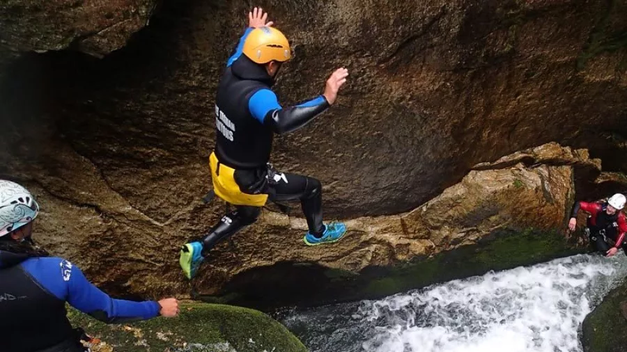 Canyoner jumping into narrow waterfall chute during Torrent River adventure