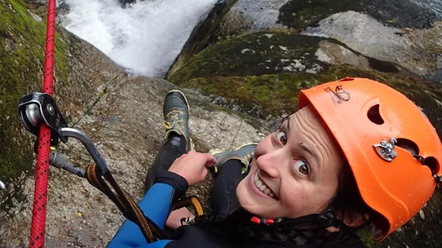 Canyoner smiling while preparing to abseil beside waterfall in Torrent River canyon