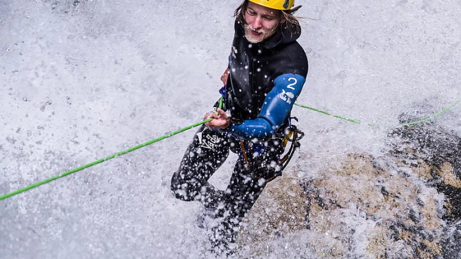 Canyoner smiling mid-descent while surrounded by whitewater spray in Waterfall Creek