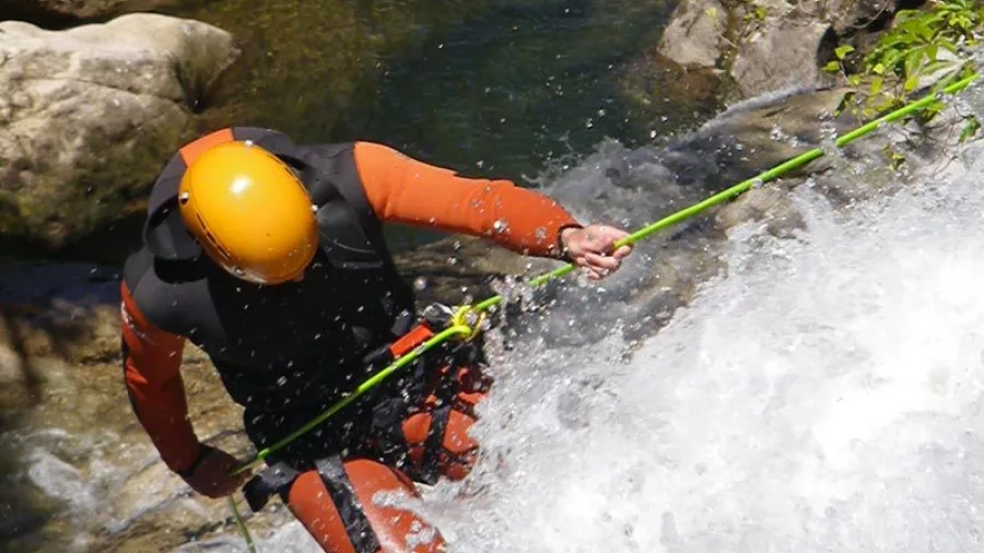 Canyoner abseiling through a powerful waterfall in Waterfall Creek canyon