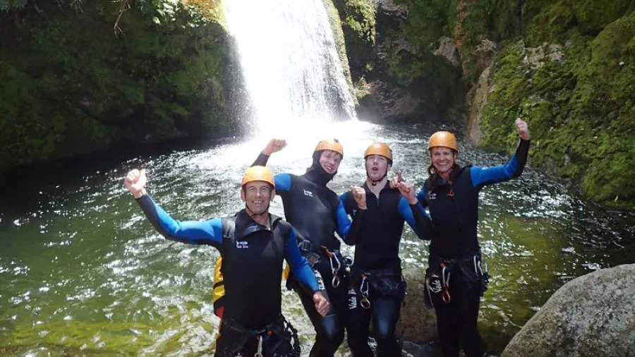 Group of canyoners celebrating below a large waterfall in Waterfall Creek canyon
