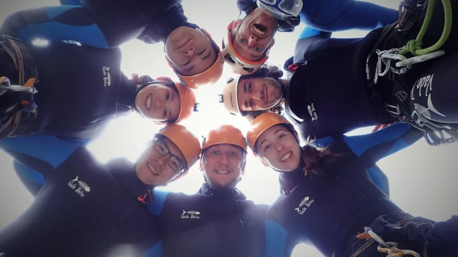 Group of canyoners smiling in a circle looking down at the camera in Abel Tasman