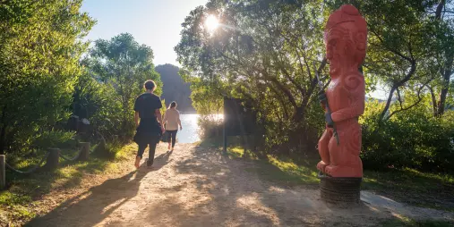 Pou of Turangapeke carved statue beside a forest track near the water in Abel Tasman National Park