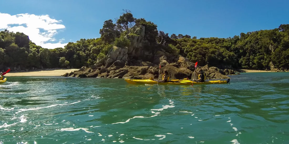 Sea kayakers exploring the turquoise waters of Mosquito Bay near Bark Bay in Abel Tasman National Park