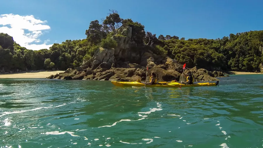 Sea kayakers exploring the turquoise waters of Mosquito Bay near Bark Bay in Abel Tasman National Park