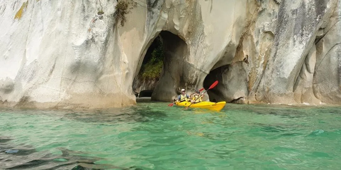 Kayakers paddling through the Tonga Arches rock formations in Abel Tasman National Park