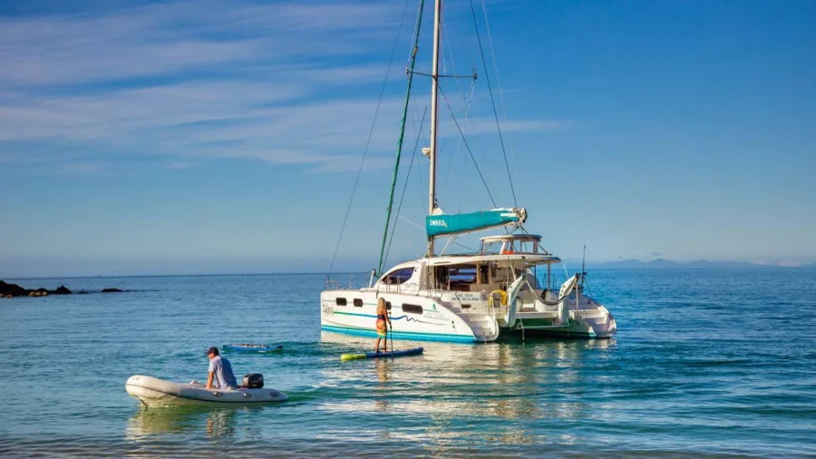 Paddleboarding from catamaran with support dinghy nearby