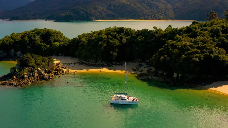 Catamaran moored in secluded emerald bay surrounded by native bush