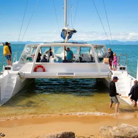 Passengers disembarking a catamaran tour on a golden Abel Tasman beach
