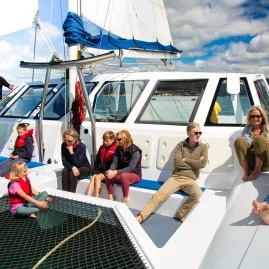 Friends enjoying the view from the catamaran foredeck in Abel Tasman
