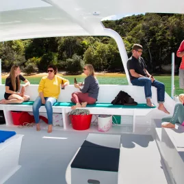 Guests relaxing on a sheltered deck during an Abel Tasman sailing tour