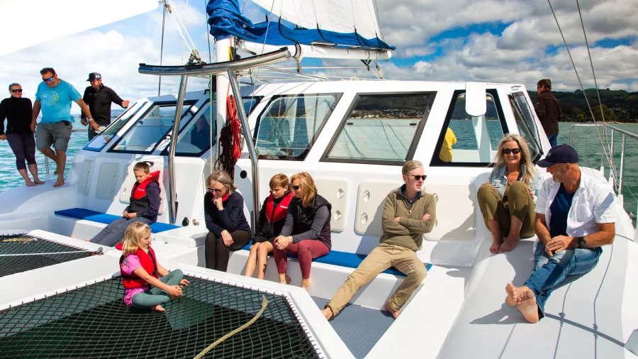Friends enjoying the view from the catamaran foredeck in Abel Tasman