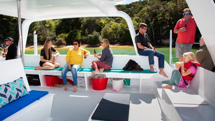 Guests relaxing on a sheltered deck during an Abel Tasman sailing tour