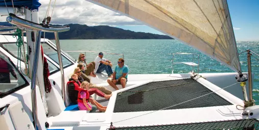 Family relaxing on deck during an Abel Tasman catamaran sailing tour