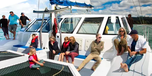 Friends enjoying the view from the catamaran foredeck in Abel Tasman