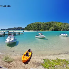 Boats and a kayak docked in the calm turquoise waters of Torrent Bay Lagoon, Abel Tasman National Park