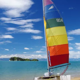 Colourful catamaran beached at Apple Tree Bay with blue skies and turquoise sea in Abel Tasman